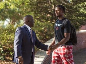 Avery Staley, right, shakes hands with a student, left, outside on campus.