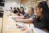 Four students assemble a diagram of a molecule at a classroom table